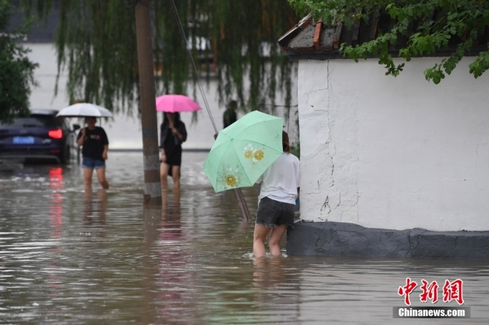 7月31日，市民行走在雨中的北京房山區(qū)瓦窯頭村。北京市氣象臺當(dāng)日10時發(fā)布分區(qū)域暴雨紅色預(yù)警信號。北京市水文總站發(fā)布洪水紅色預(yù)警，預(yù)計當(dāng)日12時至14時，房山區(qū)大石河流域?qū)⒊霈F(xiàn)紅色預(yù)警標(biāo)準(zhǔn)洪水。<a target='_blank' href='/'><p  align=