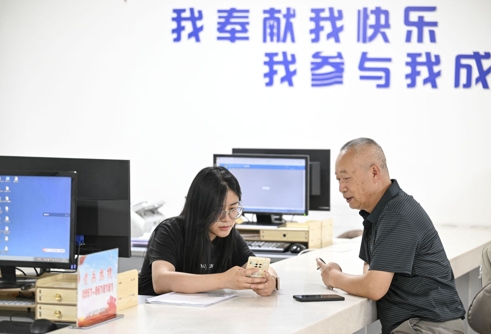 2024年6月20日，在寧夏銀川市金鳳區(qū)長(zhǎng)城花園社區(qū)黨群服務(wù)中心，工作人員幫助居民辦理業(yè)務(wù)。圖片來(lái)源 新華社