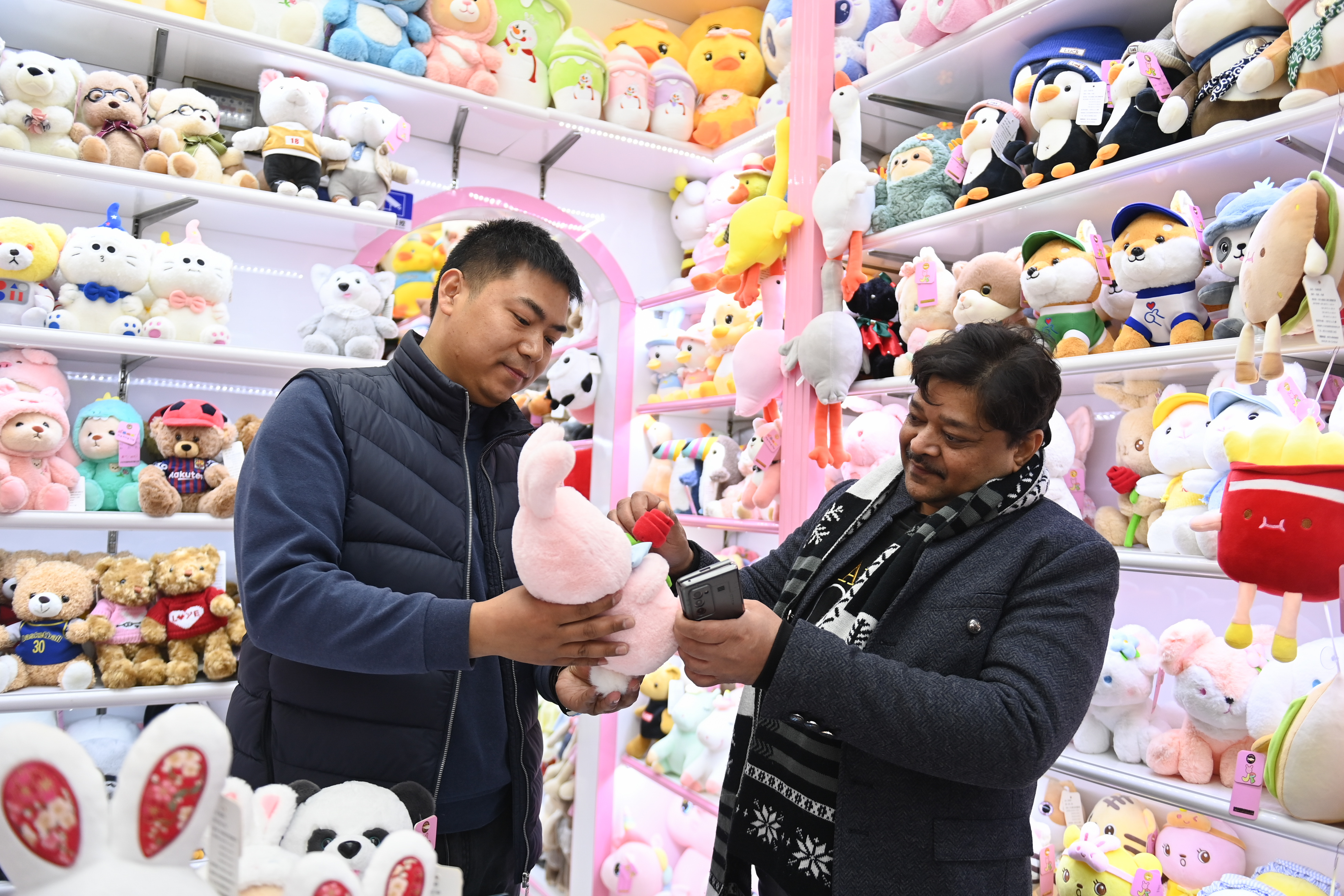 2023年2月2日，來自印度的客商（右）在義烏國際商貿(mào)城的一家玩具店鋪內(nèi)選購。