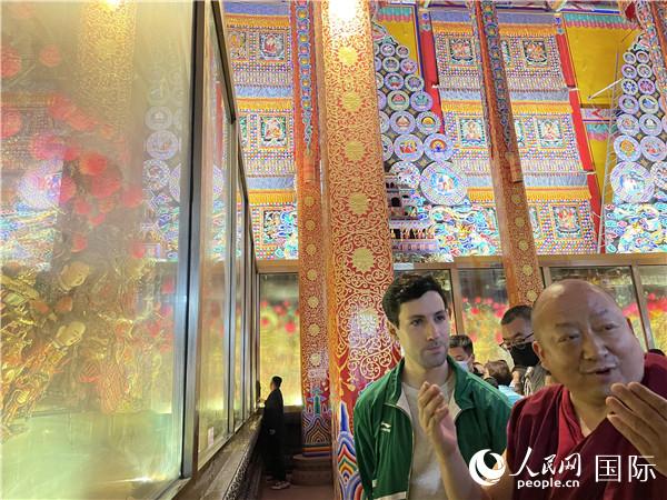 7月25日，省級非物質(zhì)文化遺產(chǎn)項(xiàng)目塔爾寺酥油花的代表性傳承人朋措堅(jiān)參（右）在塔爾寺酥油花館講解酥油花的制作過程。人民網(wǎng) 謝瑩攝