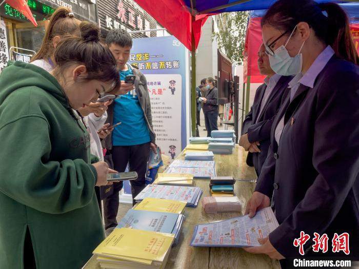 圖為工作人員正在向路過市民介紹國家反詐中心軟件的功能?！≈x牧 攝