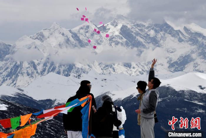 圖為5月14日，游客在西藏林芝色季拉山觀景臺拋灑“隆達(dá)”(風(fēng)馬旗，藏族民眾的一種祈福方式)?！±盍?攝